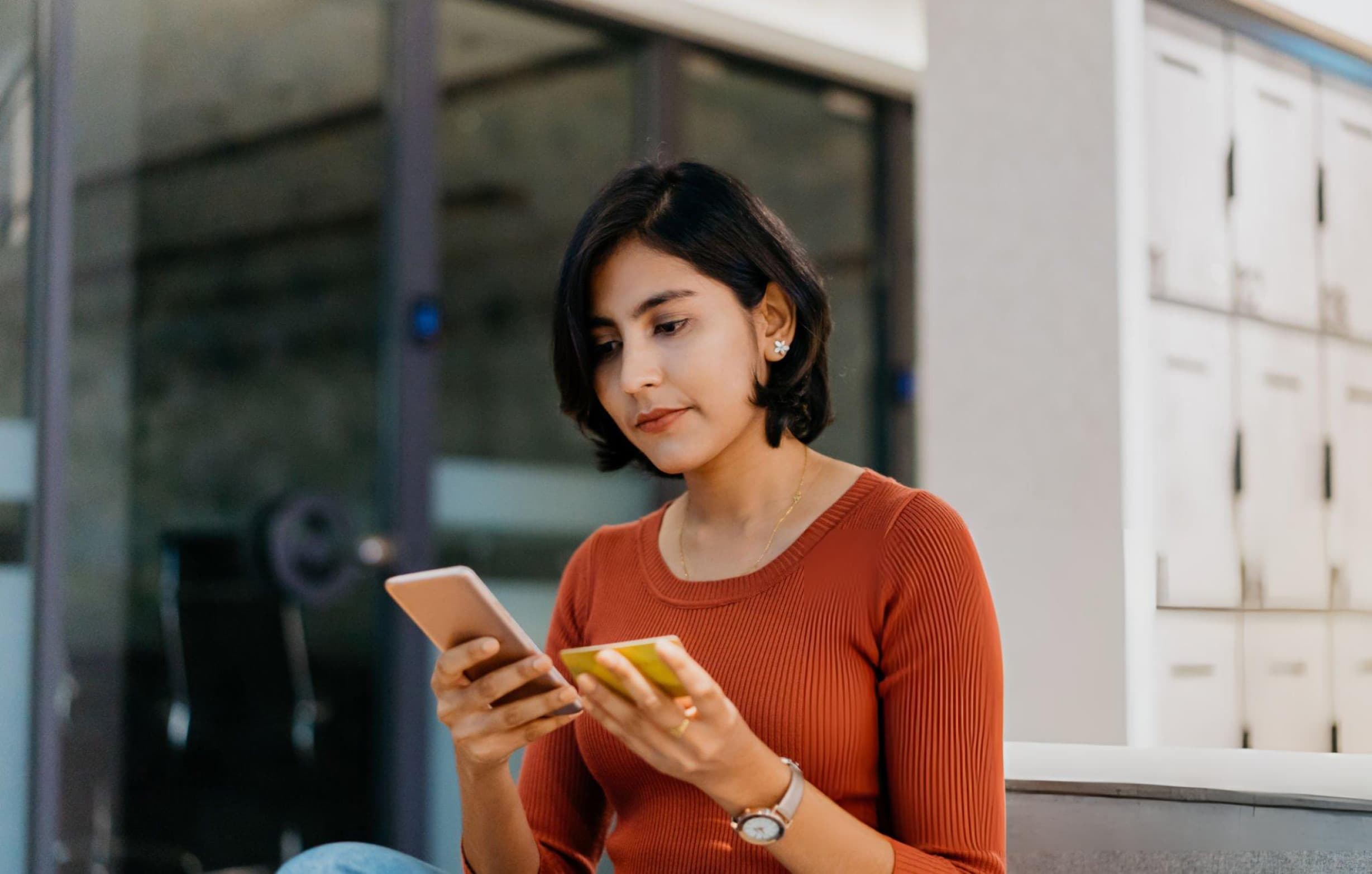 A young woman holding a phone and a payment card