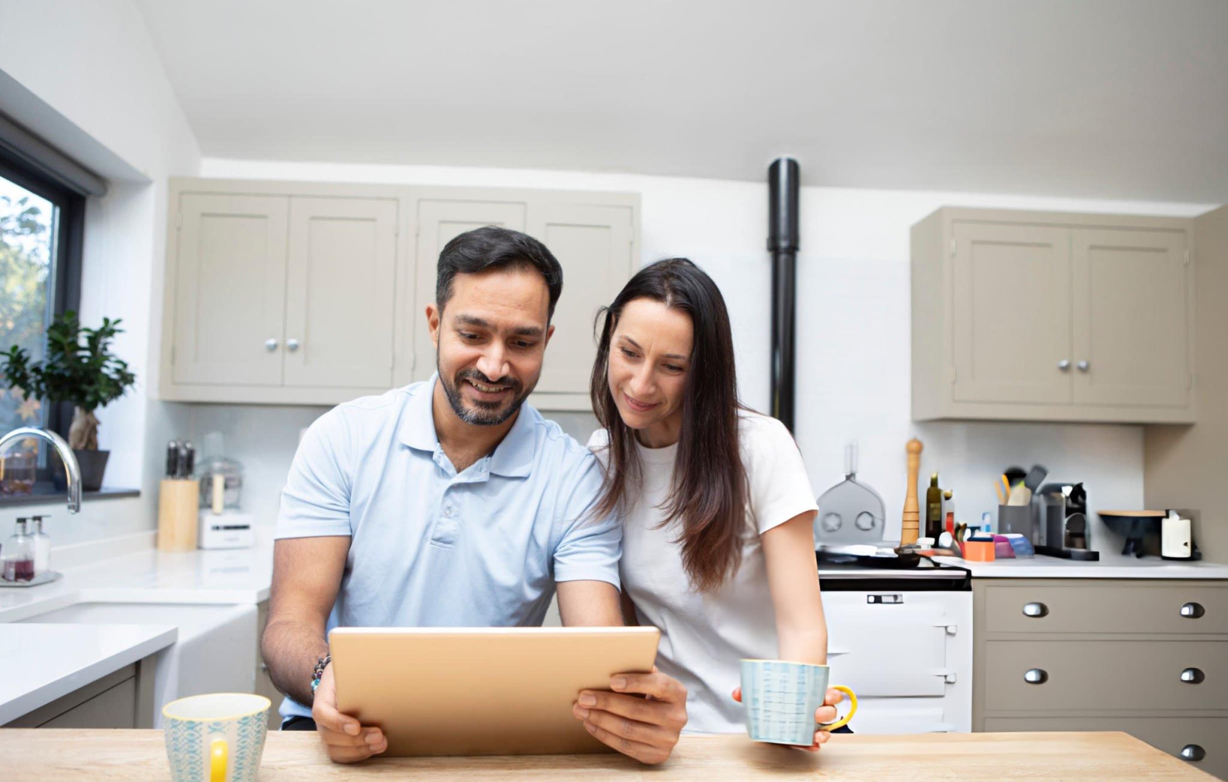 A couple reviewing their money on a tablet in a bright kitchen