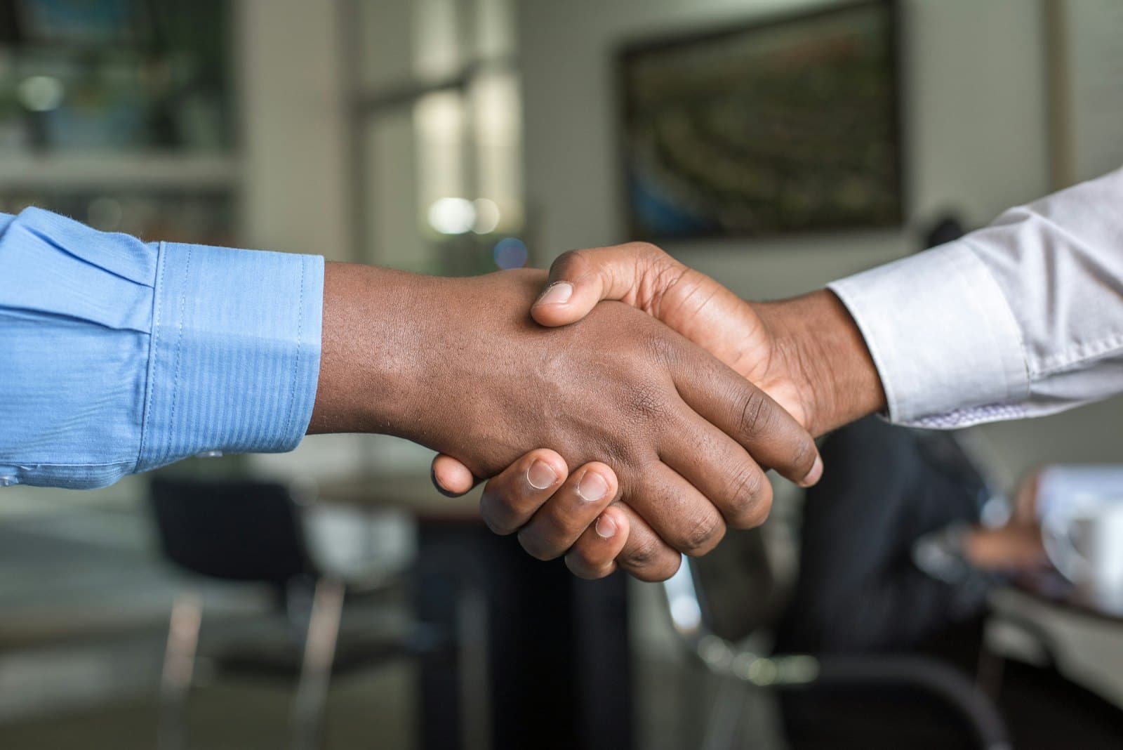 Two people shaking hands across a desk after a planning session